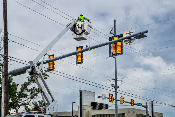 Professional light repair technician fixing pole-mounted fixtures in West Palm Beach.