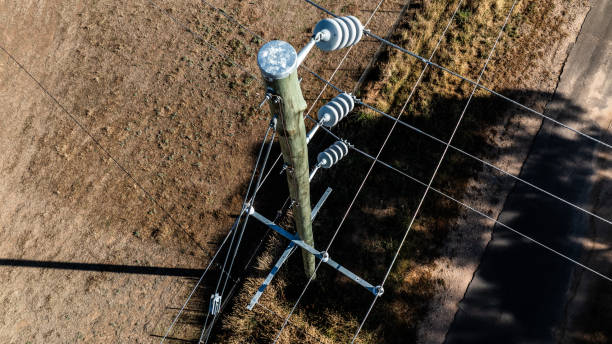 Florida pole setter positioning wooden utility pole near road.