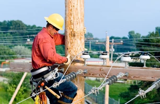 Reliable team setting utility pole using heavy equipment and precision techniques.